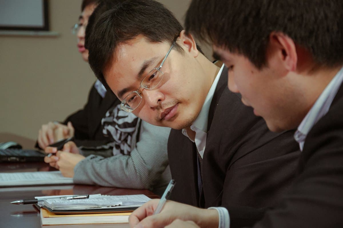 Hai người đàn ông ghi chép trong một buổi họp